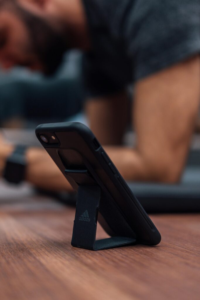 Man in plank position using a smartphone for workout routine indoors.