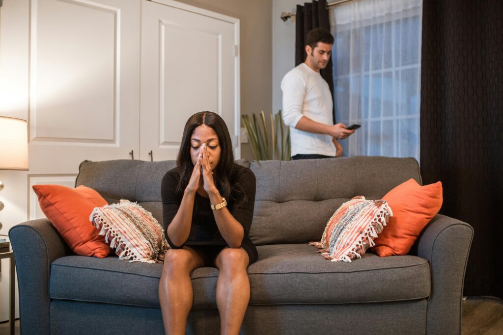 A man and woman experiencing emotional turmoil and separation in a living room setting.