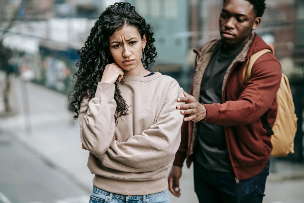 A young couple having a disagreement outdoors, displaying emotions and tension.